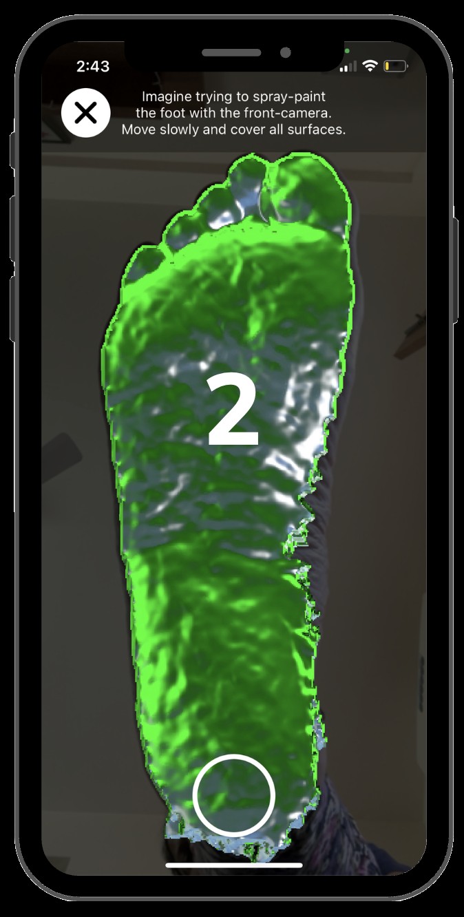An iPhone capturing a 3D foot scan, the sole overlaid with green capture coverage.